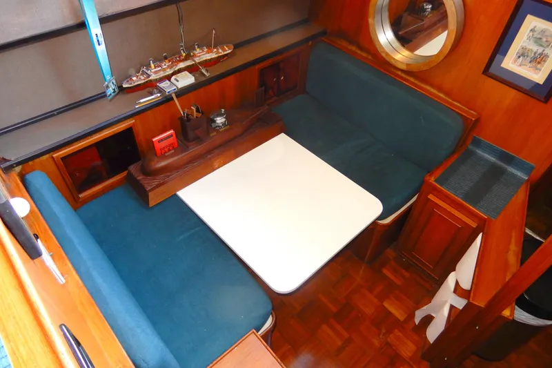 Slide: The Image of 1989 Jefferson 46 Sundeck interior with blue seating, white table, and wooden accents. - 34