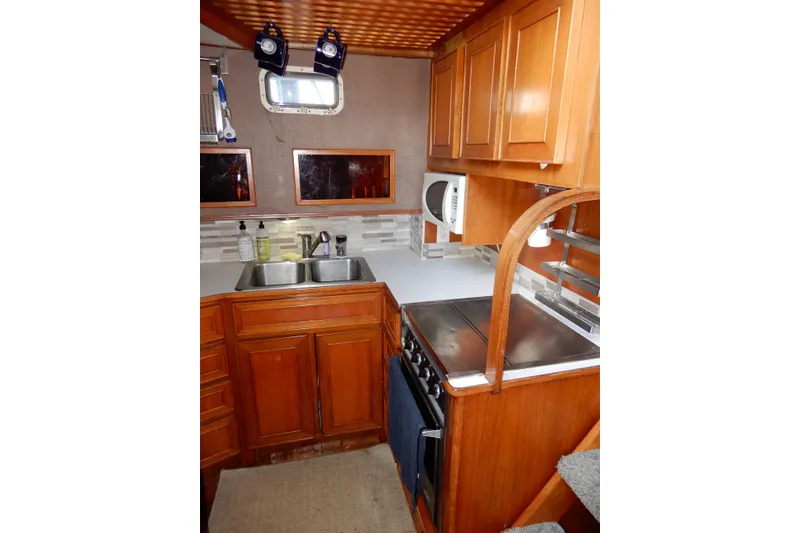 Slide: The Image of 1989 Jefferson 46 Sundeck yacht kitchen with wooden cabinets, stove, and double sink. - 35