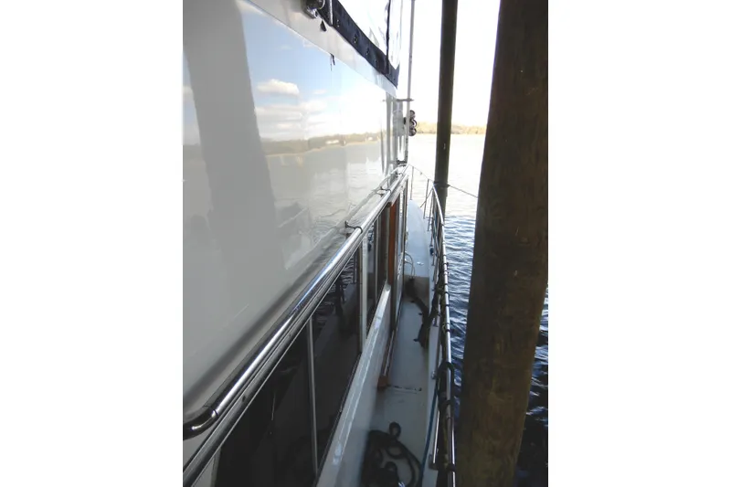 Slide: The Image of 1989 Jefferson 46 Sundeck yacht docked, side view with railing and water reflection. - 4