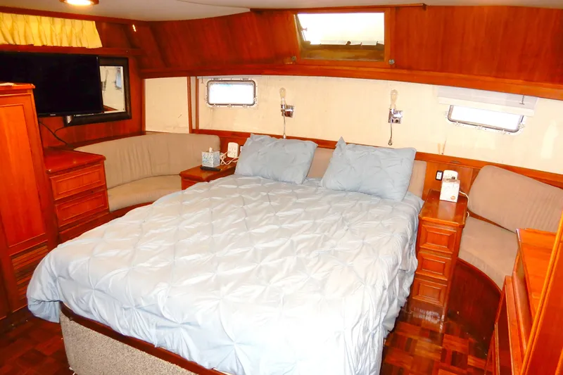 Slide: The Image of Luxurious bedroom interior of 1989 Jefferson 46 Sundeck yacht with wood paneling and cozy bedding. - 51