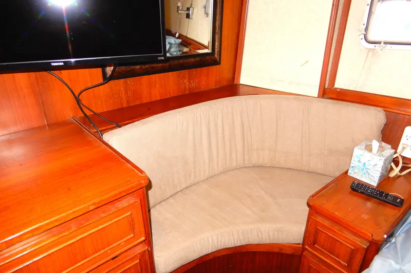 Slide: The Image of 1989 Jefferson 46 Sundeck interior with curved seating, TV, and wooden cabinetry. - 52