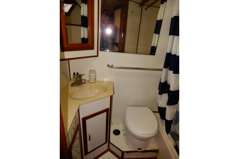 Slide: The Image of 1989 Jefferson 46 Sundeck bathroom with sink, toilet, and striped shower curtain. - 57