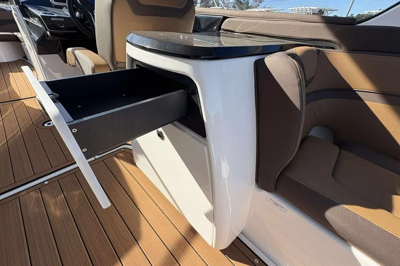 Slide: The Image of 2024 Yamaha 275 SD boat interior with open storage drawer and brown seating. - 11