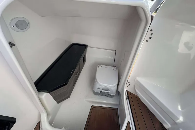 Slide: The Image of 2024 Yamaha 275 SD boat interior bathroom with compact toilet and storage cabinet. - 13