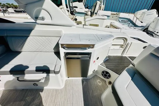 Slide: The Image of 2025 Sea Ray SDX 290 Outboard interior with seating, mini fridge, and modern design. - 8