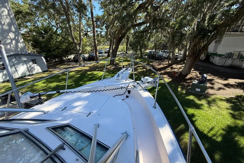 Slide: The Image of 1998 Grady-White Marlin 300 boat on grassy area, surrounded by trees and parked cars. - 23