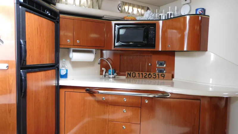 Slide: The Image of 2002 Sea Ray 380 Sundancer kitchen with wood cabinets, microwave, and fridge. - 40