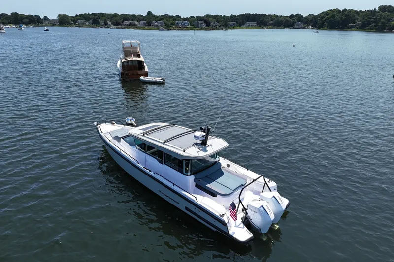 Slide: The Image of 2026 Axopar 37 XC Cross Cabin boat on calm water, with scenic shoreline background. - 11