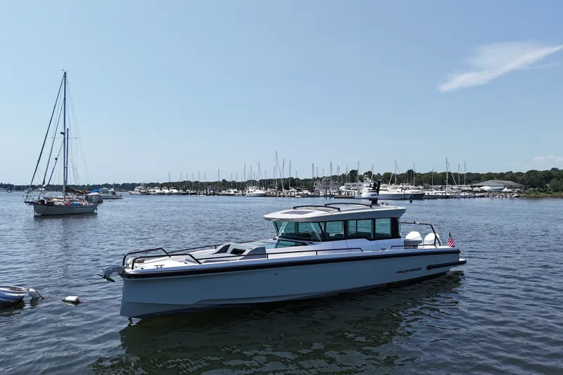 Slide: The Image of 2026 Axopar 37 XC Cross Cabin boat on calm water near marina. - 2