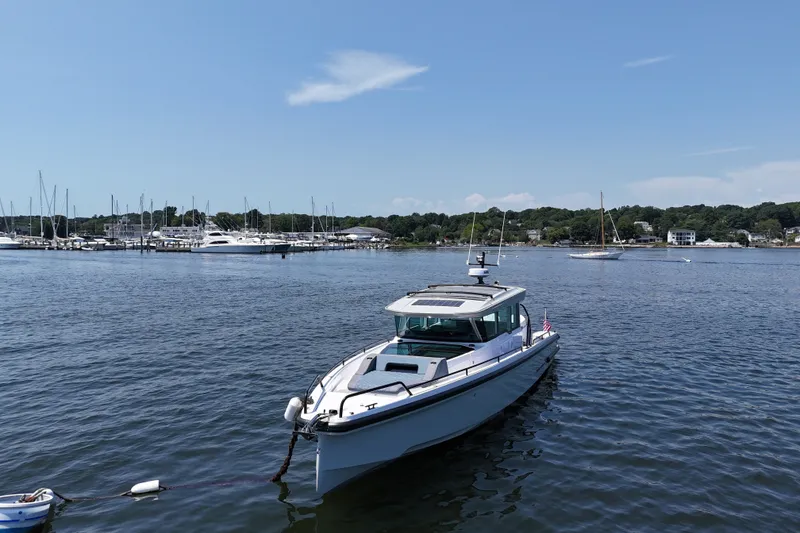 Slide: The Image of 2026 Axopar 37 XC Cross Cabin boat moored in a scenic marina under a clear blue sky. - 3
