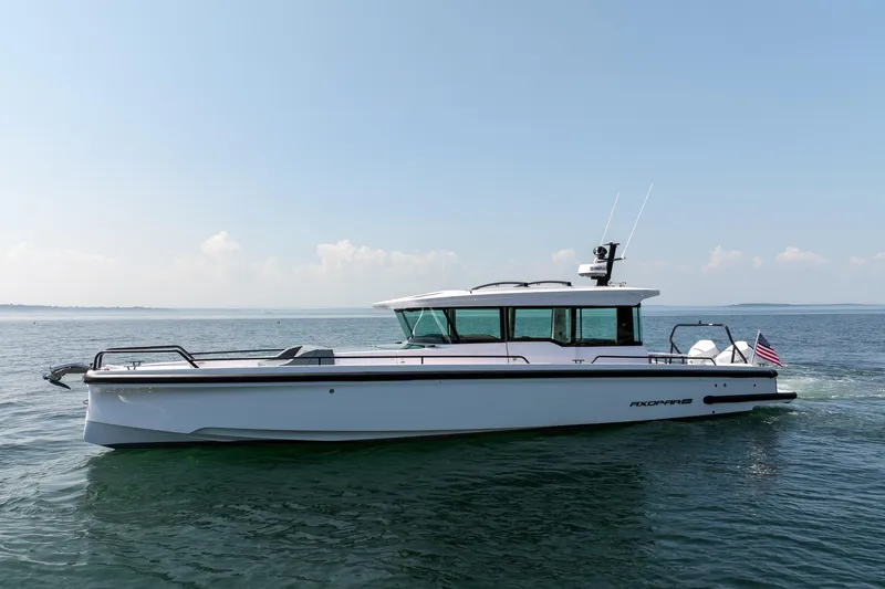 Slide: The Image of 2026 Axopar 37 Aft Cabin cruising near forested shoreline. - 5