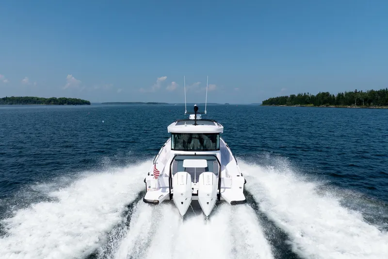 Slide: The Image of 2026 Axopar 37 Aft Cabin boat cruising on calm waters near a scenic coastline. - 9