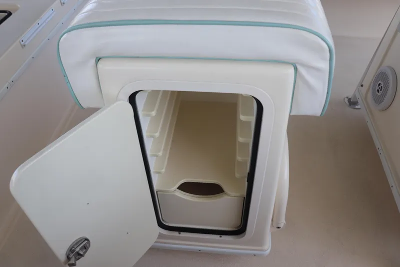 Slide: The Image of 2013 Young Boats 24 storage compartment with open door and cushioned seat. - 12