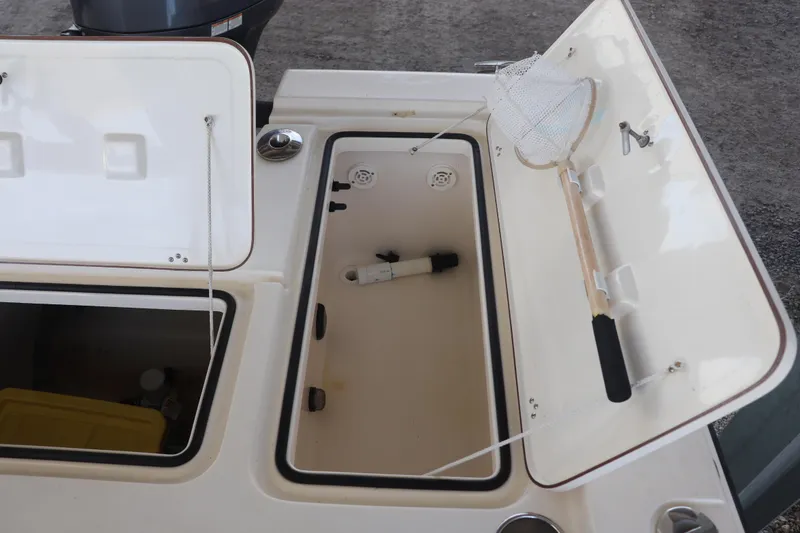 Slide: The Image of Open storage compartments on a 2013 Young Boats 24, featuring a fishing net and equipment. - 17