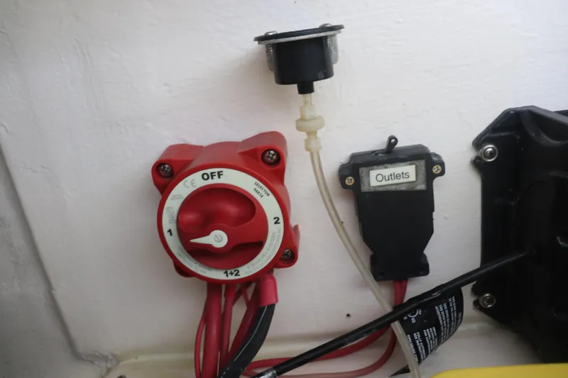 Slide: The Image of Electrical panel with red switch and labeled outlets on a 2013 Young Boats 24. - 27