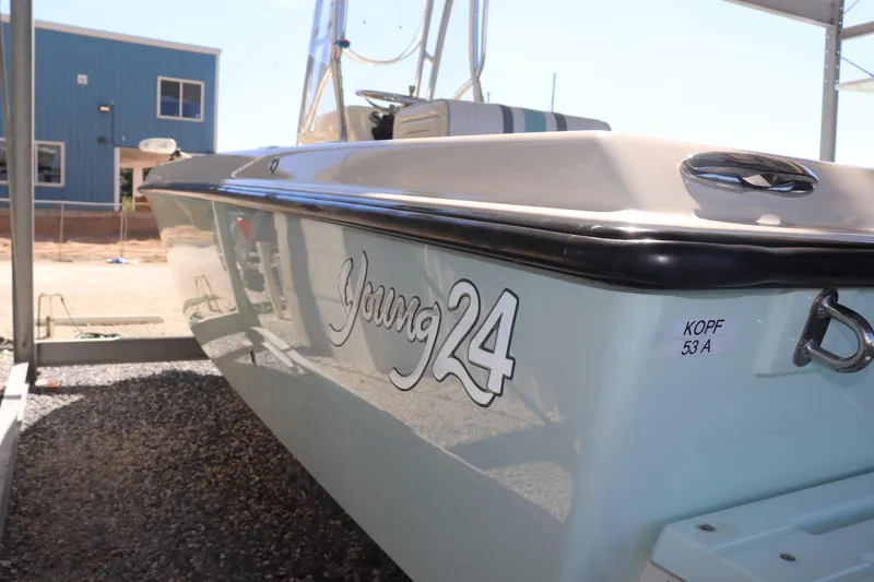 Slide: The Image of 2013 Young Boats 24 model, side view, parked outdoors near a blue building. - 6