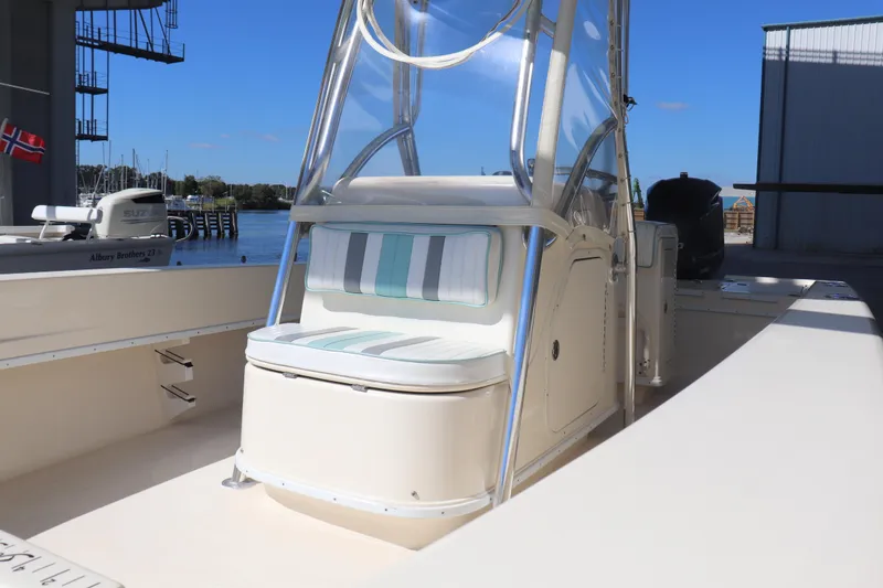Slide: The Image of 2013 Young Boats 24 model with striped seating, docked near a marina. - 7