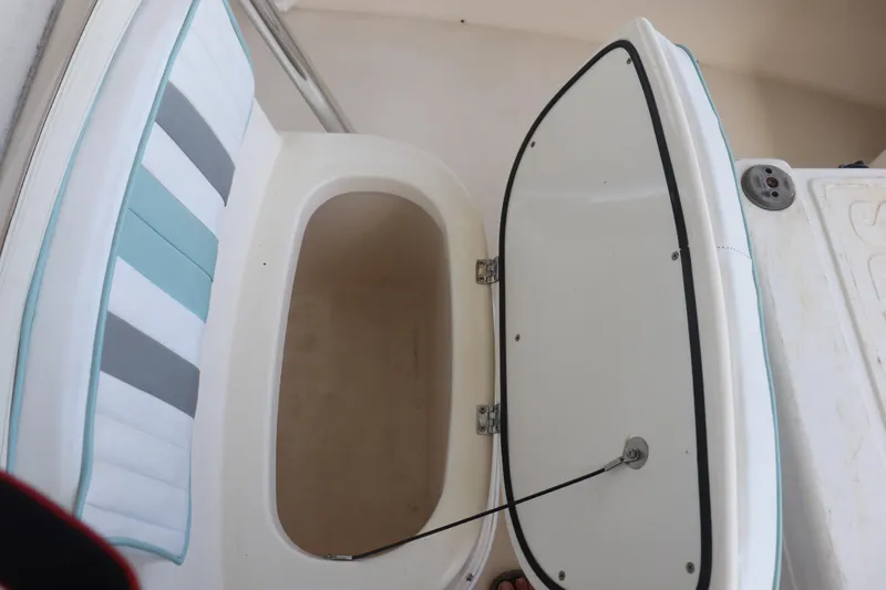 Slide: The Image of Open storage compartment on 2013 Young Boats 24, featuring cushioned seating and white interior. - 9