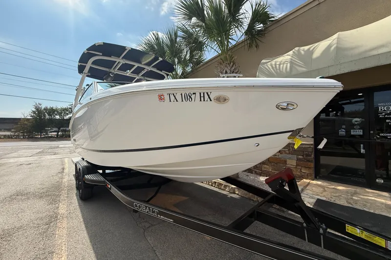 Slide: The Image of 2020 Cobalt R5 Surf boat on trailer, parked outside under palm trees. - 2