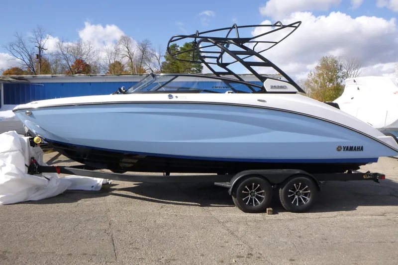The Image of 2026 Yamaha Boats 252SD on trailer, blue hull, parked outdoors. - 1