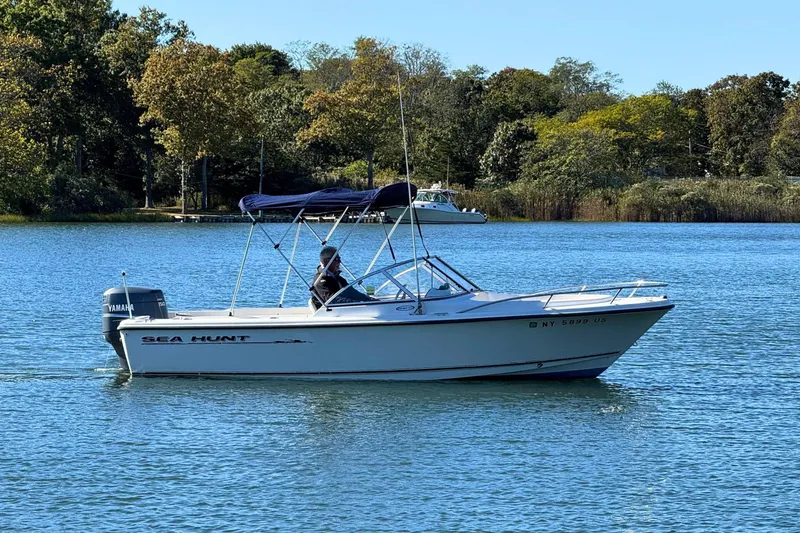 The Image of 2002 Sea Hunt Escape 200 boat on a serene lake with lush green trees. - 0