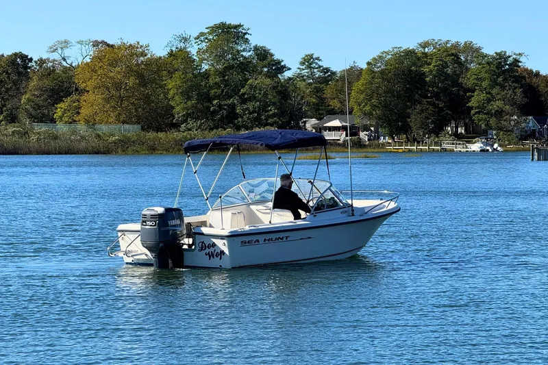 Slide: The Image of 2002 Sea Hunt Escape 200 boat on calm water with trees in the background. - 2