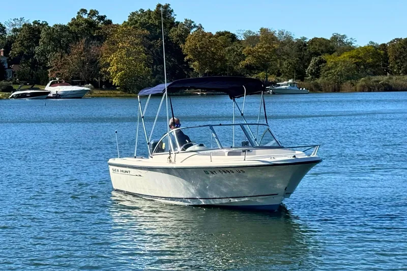 Slide: The Image of 2002 Sea Hunt Escape 200 boat cruising on a serene lake with trees in the background. - 3