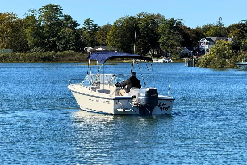 Slide: The Image of 2002 Sea Hunt Escape 200 boat cruising on a serene lake with lush greenery. - 5