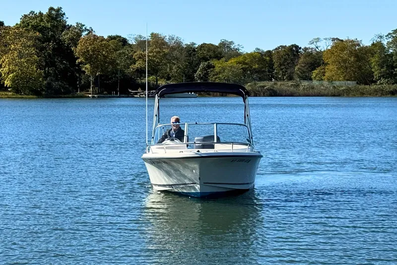 Slide: The Image of 2002 Sea Hunt Escape 200 boat cruising on a serene lake with lush green trees. - 6