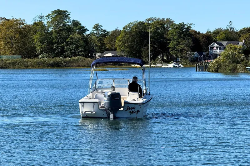 Slide: The Image of A 2002 Sea Hunt Escape 200 boat cruising on a serene lake with lush greenery. - 7