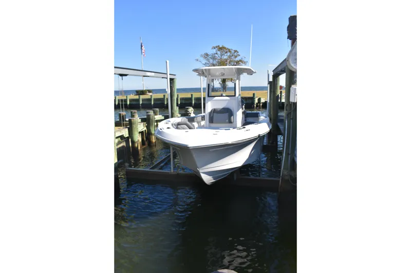 Slide: The Image of 2025 NauticStar 242L Offshore boat docked at marina under clear blue sky. - 12
