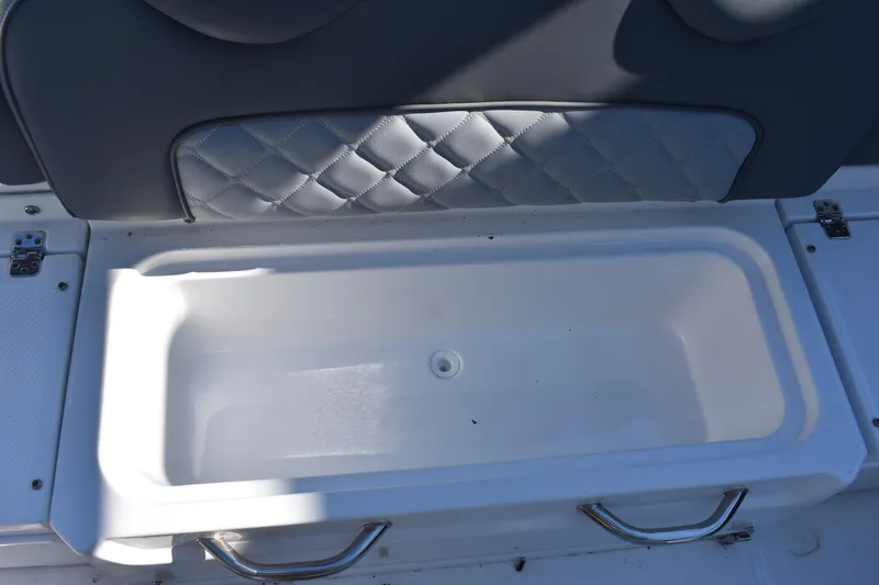 Slide: The Image of 2025 NauticStar 242L Offshore boat storage compartment with cushioned seating. - 23