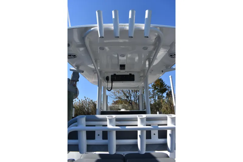 Slide: The Image of 2025 NauticStar 242L Offshore boat with rod holders and T-top under clear blue sky. - 31