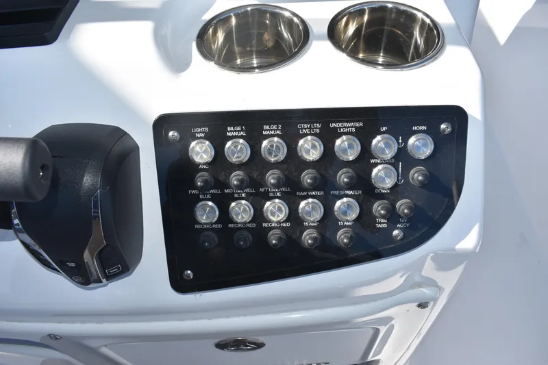Slide: The Image of Control panel of 2025 NauticStar 242L Offshore boat with switches and cup holders. - 38
