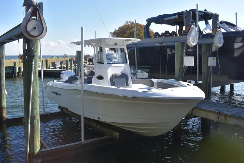 Slide: The Image of 2025 NauticStar 242L Offshore boat docked on a lift in a marina setting. - 51
