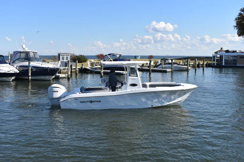 Slide: The Image of 2025 NauticStar 242L Offshore boat cruising in a marina with clear skies. - 56