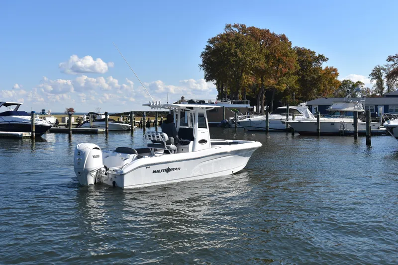 Slide: The Image of 2025 NauticStar 242L Offshore boat docked in a marina with clear skies. - 58
