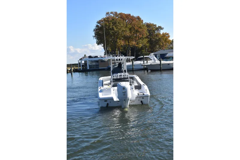 Slide: The Image of 2025 NauticStar 242L Offshore boat cruising on a calm lake near a marina. - 61