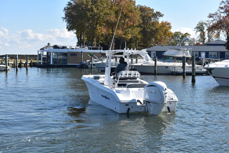 Slide: The Image of 2025 NauticStar 242L Offshore boat cruising in a marina with scenic background. - 63