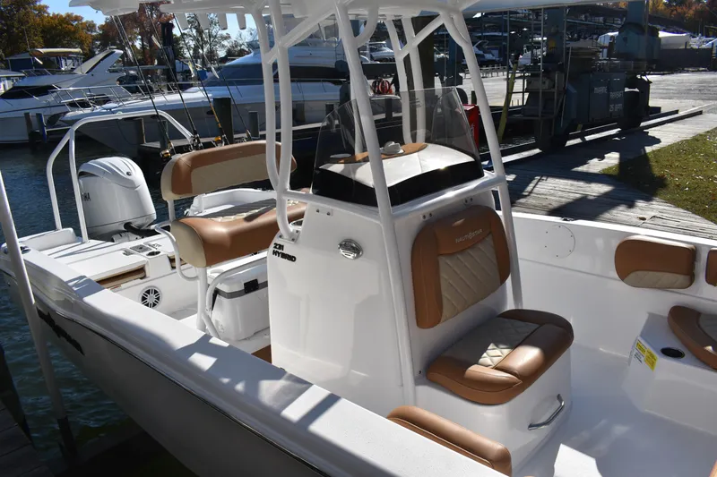 Slide: The Image of 2025 NauticStar 231 Hybrid boat with tan seating, docked at a marina. - 14