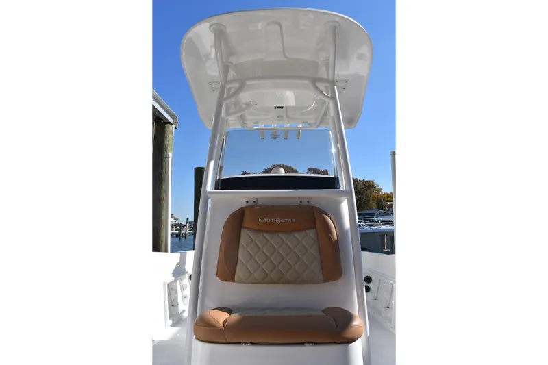 Slide: The Image of 2025 NauticStar 231 Hybrid boat with cushioned seating and T-top under clear blue sky. - 27