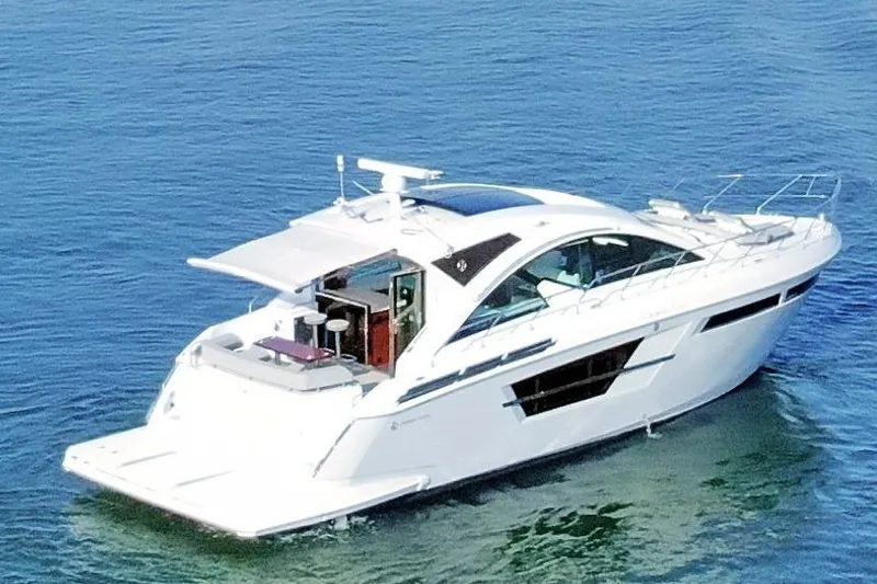 Slide: The Image of 2022 Cruisers Yachts 54 Cantius on calm blue water, showcasing sleek design. - 11