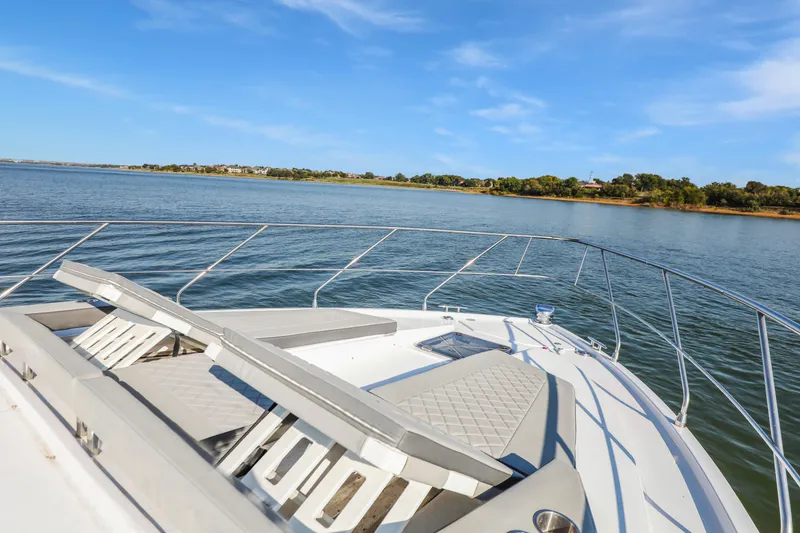 Slide: The Image of 2022 Cruisers Yachts 54 Cantius on serene water with sun loungers, clear sky. - 18