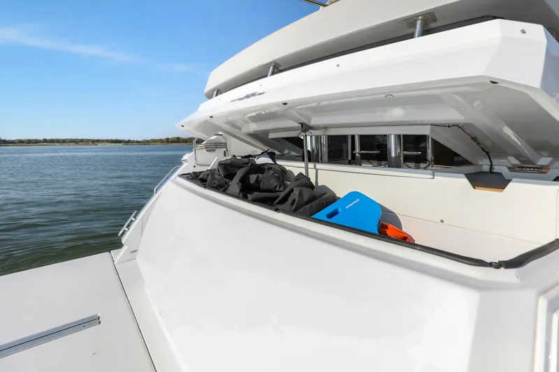 Slide: The Image of 2022 Cruisers Yachts 54 Cantius storage compartment with gear, docked on calm water. - 21