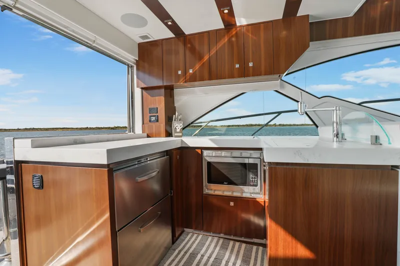 Slide: The Image of Luxurious 2022 Cruisers Yachts 54 Cantius kitchen with modern wood cabinetry and ocean view. - 44