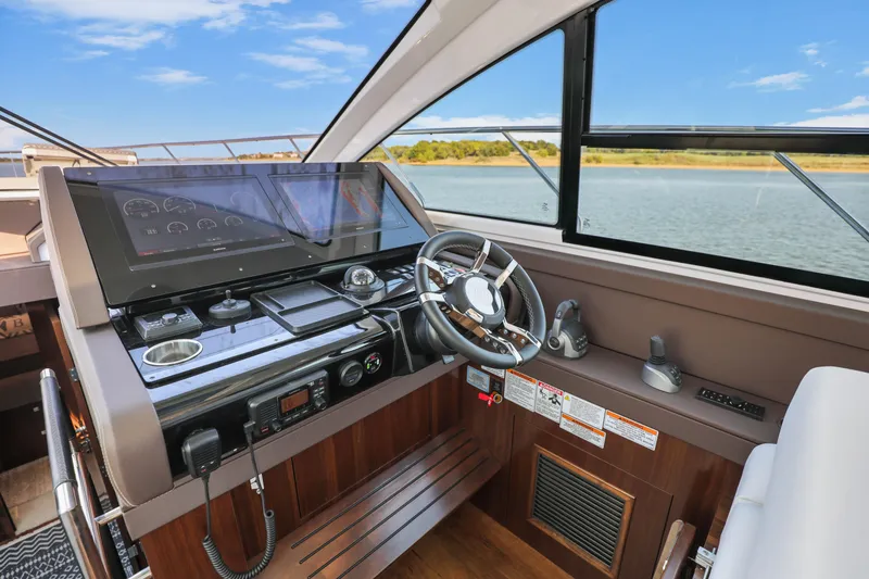 Slide: The Image of 2022 Cruisers Yachts 54 Cantius helm with modern controls and scenic water view. - 53