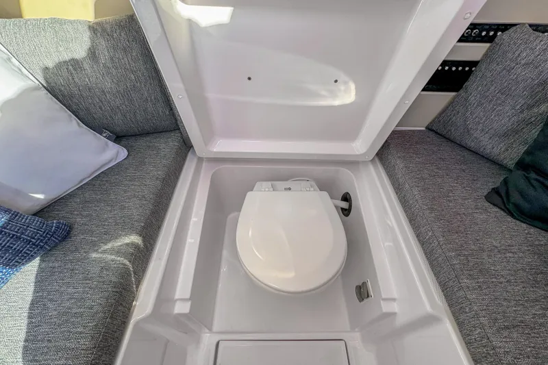 Slide: The Image of Hidden toilet compartment on 2026 Axopar 29 Sun Top boat, surrounded by gray seating. - 14