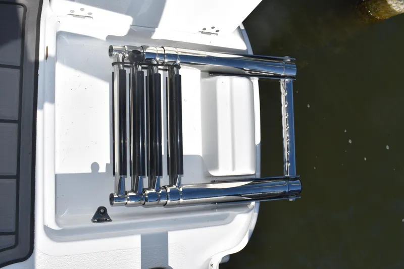 Slide: The Image of 2025 NauticStar 251 Hybrid boat ladder, folded on deck, near water. - 21