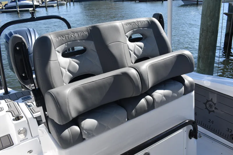 Slide: The Image of 2025 NauticStar 251 Hybrid boat seats with gray upholstery, docked by the water. - 29