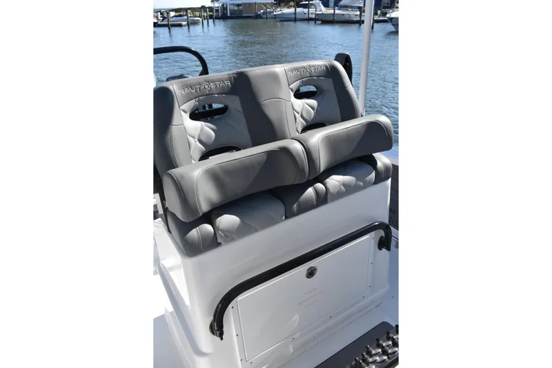 Slide: The Image of 2025 NauticStar 251 Hybrid boat seats with gray upholstery, docked by the water. - 30